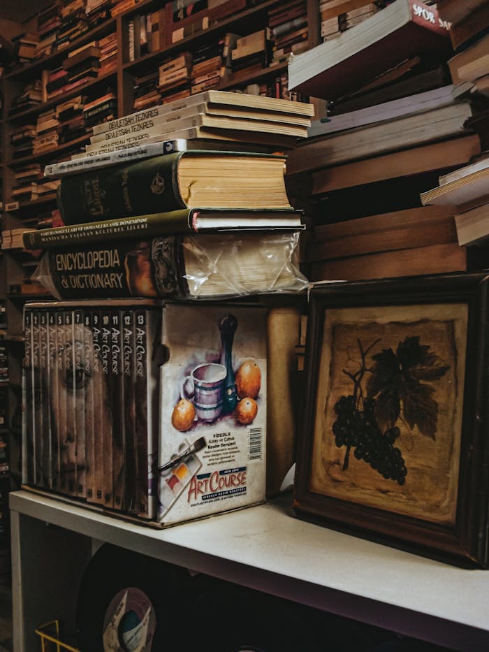 Stack of vintage books and art in a cozy secondhand store setting.